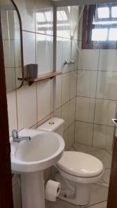 a white bathroom with a toilet and a sink at Apartamento beira-mar in Ilha Comprida