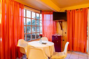 a table and chairs in a room with orange curtains at BEACH HOTEL INES en Zicatela in Brisas de Zicatela