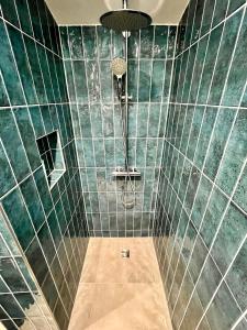 a bathroom with a shower with green tiled walls at Ocean Urban Suite in Palanga