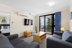 a living room with two couches and a bed at Neptune Resort in Gold Coast