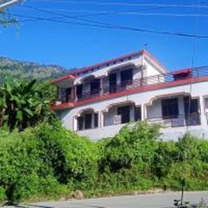 a white house with a red roof at Dana Pani Homestay by StayApart in Ukhimath