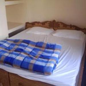 a bed with a blue and white blanket on it at Dana Pani Homestay by StayApart in Ukhimath