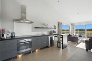a kitchen with a counter top and a living room at Hurunui River Retreat - Flax Cottage in Hurunui +13 photos