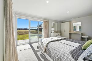 a bedroom with a bed and a large window at Hurunui River Retreat - Flax Cottage in Hurunui