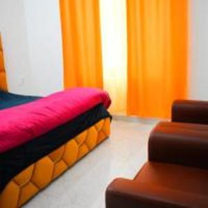 a bedroom with orange curtains and a red bed at Hotel The Yamuna by StayApart in Kharsālī +8 photos