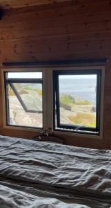 a bedroom with a bed and two windows with the view at Original Architecture In Southern Norway in Søndeled +25 photos