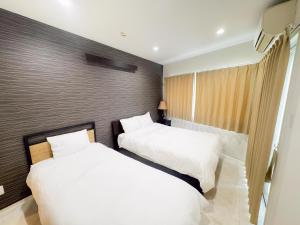 two beds in a hotel room with white sheets at 恩納村仲泊海の見える2LDkアパート in Onna