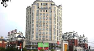 a tall white building in the middle of a city at GreenTree Inn Tongling City ZonGYAng County Qishan Road People's Hospital in Zongyang