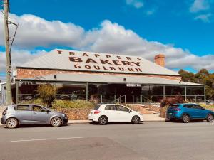 two cars parked in front of a bakery with a building at The Bakehouse Motel in Goulburn
