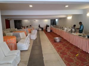 un comedor con sillas blancas y un bar en Hotel Prem Ratna, en Dehradun 29 fotos más