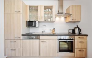 a kitchen with wooden cabinets and a sink and a microwave at Ferienwohnung Pörtschach in Pörtschach am Wörthersee
