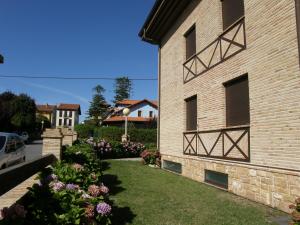 a brick building with a yard with flowers at Apartamentos la Marina in Ribadesella