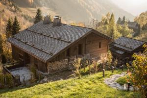 a small wooden house on a hill with mountains in the background at Chalet 1864 in Le Grand-Bornand