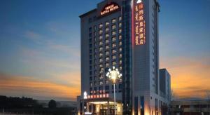 a hotel building with a sign on it at sunset at Venus Royal Hotel Ordos Yijinhuoluo Banner Olympic in Ordos