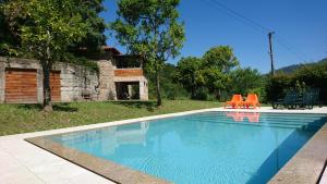 a swimming pool with orange chairs in a yard at Quinta da Bouça - Agroturismo in Paços de Gaiolo +38 photos
