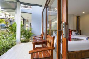 - une chambre avec un lit et deux chaises sur une terrasse couverte dans l'établissement Suối Mây Garden Resort & spa, à Duong Dong