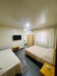 ein Hotelzimmer mit zwei Betten und einem Flachbildfernseher in der Unterkunft Casa de huéspedes in Puerto Iguazú