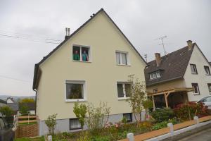 two people in the window of a white house at Ferienwohnung Schadler in Windeck