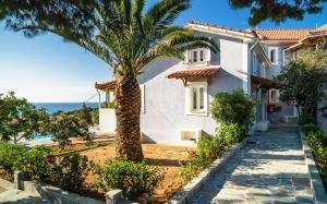 a villa with a palm tree in front of a house at Villa Eliza in Skala