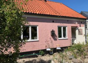 una casa rosa con techo naranja en Mysigt stenhus i Simrishamn, en Simrishamn
