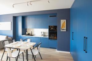 Una cocina con gabinetes azules y una mesa y sillas. en VacationClub - Let's Sea Baltic Park Apartament F96, en Gąski