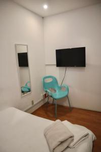 a bedroom with a blue chair and a flat screen tv at Habitación privada en Polanco cerca del Metro in Mexico City