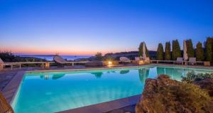 a large swimming pool with blue water at night at Villas Agia Irini Cove in Agia Irini Paros