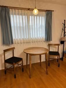 een tafel en twee stoelen in een kamer met een raam bij 白樺ハウス女性&家族専用 送迎ありペット可 in Chigasaki