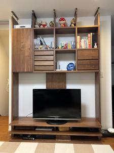 een entertainmentcentrum met een televisie in de woonkamer bij 白樺ハウス女性&家族専用 送迎ありペット可 in Chigasaki