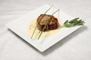 eine weiße Platte mit einem Stück Fleisch mit Soße in der Unterkunft Hotel Pucon Green Park in Pucón