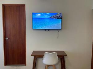 a flat screen tv on a wall with a table and a chair at Casa Lú in Santa Cruz Huatulco +19 photos