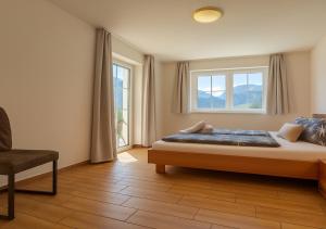 a bedroom with a bed and a chair and a window at Appartementhaus Flattach in Flattach +114 photos