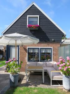 una casa con un sofá y una mesa y una sombrilla en Sonne, en Egmond aan Zee