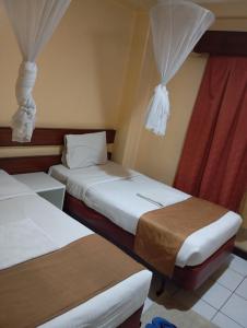 two beds in a hotel room with curtains at Kapok hotel B&B in Nairobi