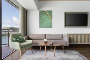 a living room with a couch and two chairs and a tv at Dusit Beach Resort Guam in Tumon