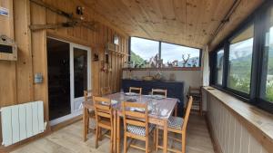a dining room with a table and some windows at Le CHALET AUX CERFS in Campan