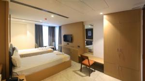 a hotel room with two beds and a mirror at Roots Luxury suits & Banquets in Bangalore