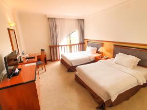 a hotel room with two beds and a television at Parkview Hotel in Kampong Jerudong