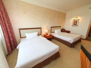 a hotel room with two beds and a table with a lamp at Parkview Hotel in Kampong Jerudong
