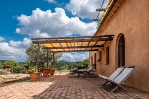 a patio with a table and chairs under a pergola at Casale Poggio Rocco in Manciano
