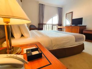 a hotel room with a bed and a desk with a phone at Parkview Hotel in Kampong Jerudong