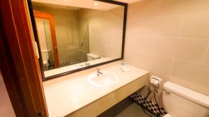 a bathroom with a sink and a mirror and a toilet at Parkview Hotel in Kampong Jerudong
