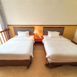 a hotel room with two beds and a table with a lamp at Parkview Hotel in Kampong Jerudong