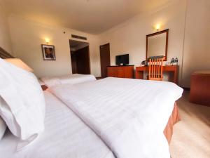 a hotel room with two beds and a mirror at Parkview Hotel in Kampong Jerudong