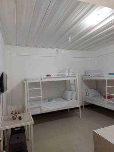 a room with three white bunk beds in a room at RedDoorz at Wyns Hotel in Silañgang Mayao