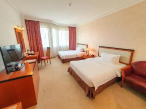 a hotel room with two beds and a flat screen tv at Parkview Hotel in Kampong Jerudong