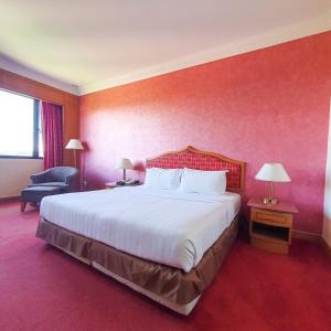 a hotel room with a large bed and a chair at Parkview Hotel in Kampong Jerudong