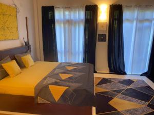 a bedroom with a bed with yellow sheets and curtains at New Palms Villa Induruwa Homestay in Induruwa