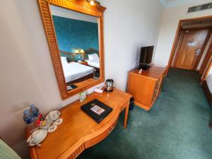 a hotel room with a mirror and a wooden table at Parkview Hotel in Kampong Jerudong