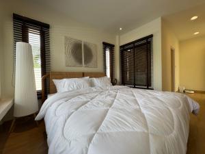 a large white bed in a bedroom with windows at SandScape Pool Villa A in Ban Nong Khao Nieo